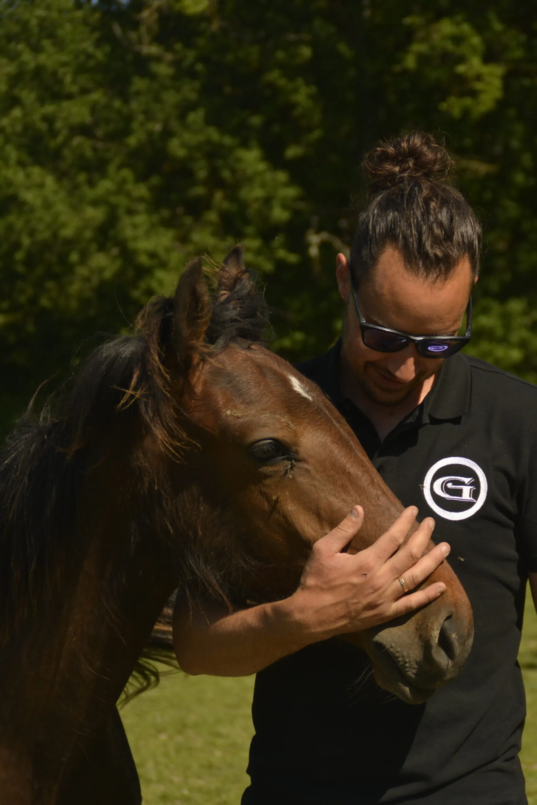 Un éleveur de Groboz caressant le visage d'un jeune cheval Barbe